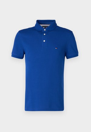 Blue polo shirt in cotton. Features a classic collar, three-button placket, and a small logo on the left chest. Short sleeves.