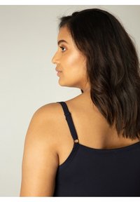 Marineblauw hemdje met dunne verstelbare bandjes en een zachte, rekbare textuur. De achterkant heeft een ronde hardwarefunctie.