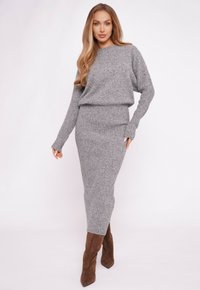 Szary prążkowany sweter dzianinowy i pasująca do niego sp�ódnica midi, tkanina o fakturze, luźny krój, długie rękawy, zestawione z brązowymi kozakami do kolan na obcasie.