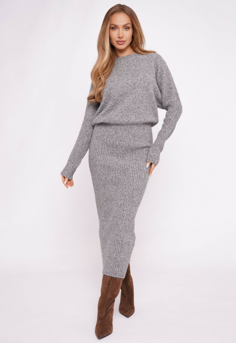 Szary prążkowany sweter dzianinowy i pasująca do niego spódnica midi, tkanina o fakturze, luźny krój, długie rękawy, zestawione z brązowymi kozakami do kolan na obcasie.