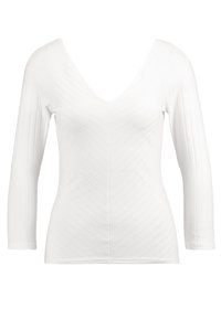 White long-sleeve top with a deep V-neck, featuring a ribbed texture and vertical stripe pattern, fitted design. Smooth fabric finish.