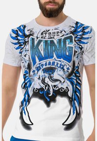 Weißes Baumwoll-T-Shirt mit blauer Grafikdruck, der das Wort "KING" und Flügeldesigns zeigt, runder Ausschnitt und kurze Ärmel.