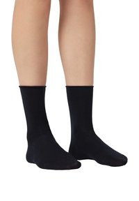 Calcetines de algodón negros con una textura suave, de longitud media en la pantorrilla y puños elásticos, que ofrecen un ajuste ceñido alrededor de los tobillos.