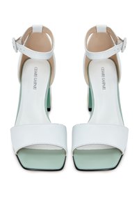 Sandales à talons ouvertes blanches avec des brides autour de la cheville, semelles intérieures carrées vert menthe et talons épais, vues de dessus.