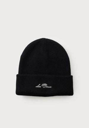 Bonnet en tricot noir avec revers plié présentant un texte brodé blanc "Les Deux" sur un fond clair uni.