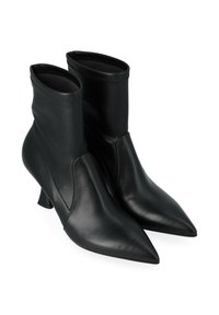 Bottines en cuir noir avec des bouts pointus et des talons fins de hauteur intermédiaire sur fond blanc.