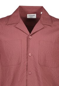 Camicia a maniche corte, taglio regolare, in un tessuto rosa polveroso testurizzato, con due tasche sul petto e bottoni rosa abbinati.