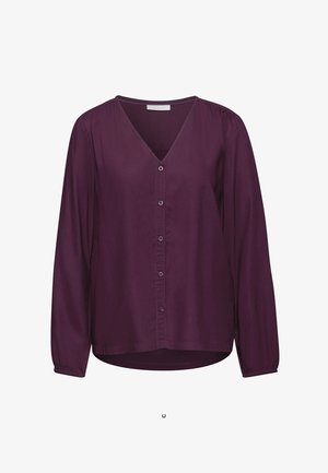 Blouse à manches longues en V de couleur violet profond, fabriquée dans un tissu lisse. Elle présente des boutons sur le devant, des poignets froncés et un ourlet légèrement incurvé.