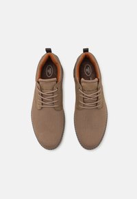 Baskets en mesh marron avec des accents marron doux, forme arrondie, lacets et surface texturée. Comprend un logo sur la languette et une semelle cousue.