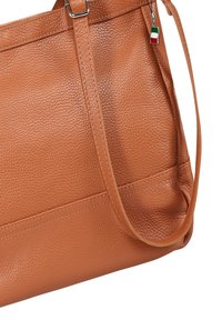 Braune Lederhandtasche mit strukturierter Oberfläche, ausgestattet mit einem einzelnen Schulterriemen und einem dekorativen Charme der italienischen Flagge.