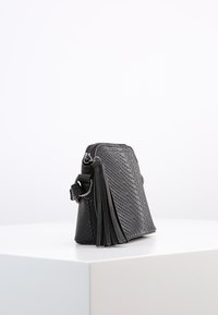 Borsa nera in pelle intrecciata con forma rettangolare, caratterizzata da un nappa laterale e chiusura con zip. Texture liscia con design strutturato.