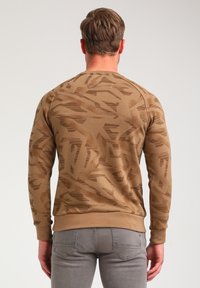 Pruun sweatshirt, millel on tekstureeritud geomeetriline muster, soonikud küünarvarrastes ja allservas ning ümar kaelus. Valmistatud pehmest ja mugavast kangast.