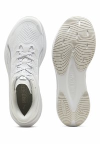 Chaussures de sport blanches avec dessus en mesh respirant, col rembourré et semelle extérieure en caoutchouc texturée présentant des motifs ondulés et un logo.