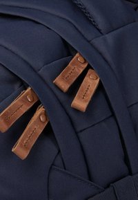 Marinefarbener Stoffrucksack mit braunen Lederelementen und Verschlüssen. Verfügt über mehrere Fächer und gestickte Details für zusätzliche Textur.