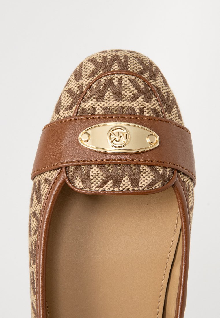 Braune, gemusterte Stoffflats mit einem Lederband, das an der Vorderseite mit einem goldfarbenen Logo-Highlight versehen ist. Runde Zehenform.
