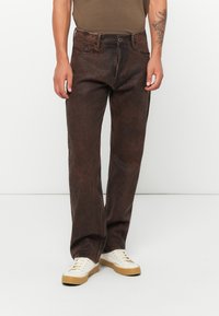 Brune denimjeans med en lett falmet tekstur og vanlig passform, med tradisjonelle lommer, knappelukking og slitte detaljer.