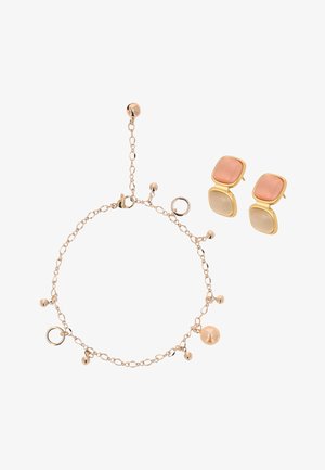 Armband in Goldoptik mit kleinen Anhängern und rundem Pfirsich-Perle, kombiniert mit goldgerahmten Doppel-Quadrat-Ohrsteckern in Rosa- und Beigetönen.