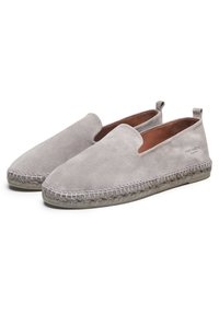 Graue Slipper aus Wildleder mit abgesteppten Kanten und einer flachen, gewebten Sohle. Glatte Textur, minimalistisches Design mit seitlichen Laschen für einfaches An- und Ausziehen.