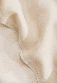 Beige strukturiertes Gewebe mit einem dezenten Muster, das einen sanften Glanz und eine gewebte Oberfläche aufweist. Das Material wirkt weich und fällt fließend.