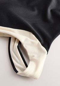 Gros plan d'un tissu lisse noir et blanc avec des bords pliés montrant la texture et les détails des coutures.