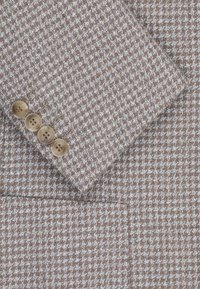 Brązowy materiał w kratę houndstooth z teksturowanym wzorem i jasnoniebieskimi akcentami. Cztery beżowe guziki na mankiecie z delikatnym połyskiem.