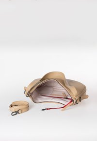 Beige leren handtas met een gestructureerde vorm, ritssluiting en een gestreepte binnenkant met rode accenten; inclusief een afneembare band.