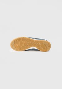 Shoe sole featuring a honeycomb pattern in rubber for traction, with a grey and white upper. Durable material with textured surface details.