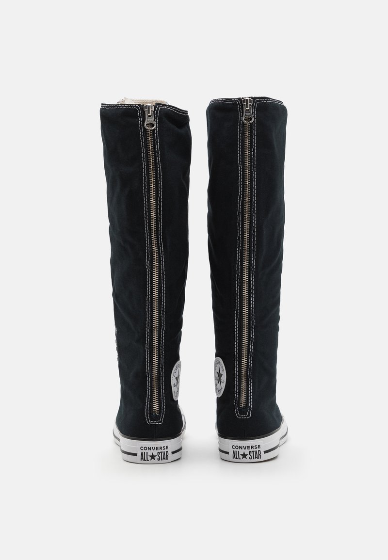 Black canvas knee-high boots with silver zippers, featuring Converse All Star branding. The design includes white soles and a textured finish.