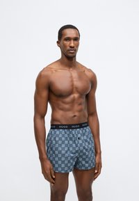Μπόξερ με μπλε και γκρι γεωμετρικό σχέδιο, ελαστική μαύρη μέση με τη σήμανση "HUGO", κατασκευασμένα από μαλακό ύφασμα.