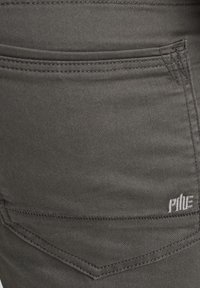 Dark gray denim fabric featuring a five-pocket design with subtle stitching and a small logo on the back pocket. Smooth texture.