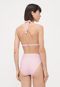 Bikini roz și alb cu dungi, cu guler halter și legătură reglabilă. Pantaloni înalți cu acoperire moderată și o textură netedă.