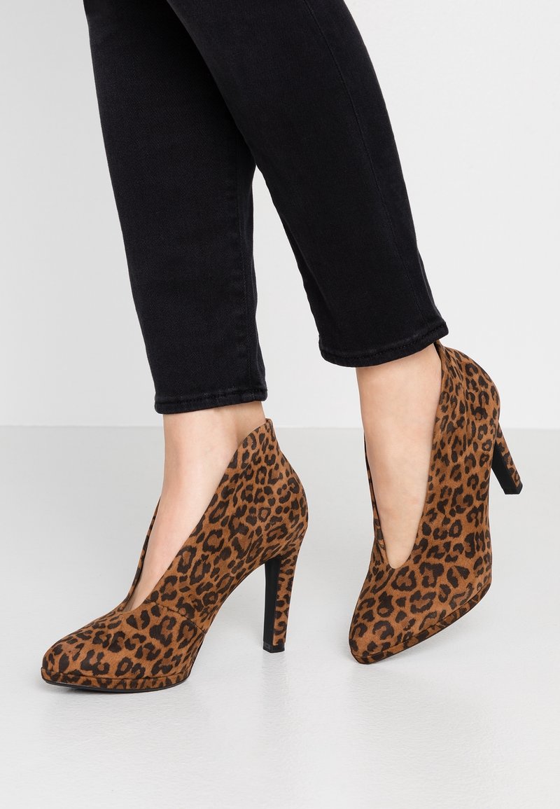 Escarpins en suède à imprimé léopard, avec un bout pointu, un design en V et un talon aiguille noir. Semelle en cuir texturé brun avec des taches sombres.