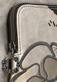 Pochette in pelle dorata metallica con cerniera nera, caratterizzata da un design floreale embossato e un charm decorativo con lettere attaccate.