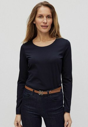 Marineblauw langemouwen shirt met een ronde hals, gemaakt van zachte stof. G gedragen met donkere jeans en een bruine riem met een decoratieve gesp.