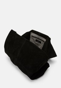Black suede bag, folded with a textured surface. Interior features a striped lining. Contains a subtle logo tag inside.