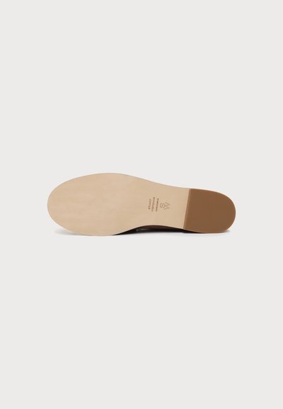 Semelle plate de chaussure avec avant et intercalaire beige clair, talon brun foncé, et petit texte imprimé près de la zone de la voûte plantaire.
