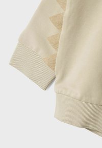 Felpa beige con polsini a coste e un motivo triangolare decorativo in una tonalità più chiara lungo la manica.