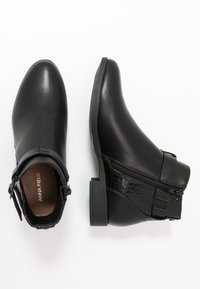 Bottes noires à la cheville en cuir lisse avec un motif crocodile texturé au talon. Elles disposent d'une fermeture éclair latérale et d'un talon épais et carré.