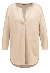 Top beige leggero con scollatura a V, maniche a tre quarti e una leggera lucentezza. Presenta un orlo posteriore leggermente più lungo e finiture cucite.