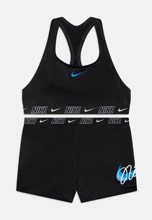 Conjunto de sujetador deportivo y pantalones cortos negros hecho de material elástico. Presenta un logo de Nike azul y letras blancas en contraste en la cinturilla.