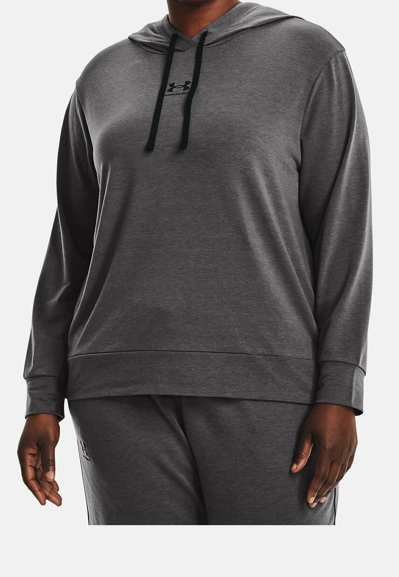 Personne portant un sweat à capuche Under Armour gris foncé à manches longues et un pantalon de survêtement assorti, montrant le torse et les bras sur un fond uni.