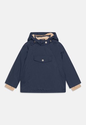 Veste à capuche bleu marine avec doublure intérieure beige, poche à rabat avant avec bouton et détails beiges aux poignets des manches longues.