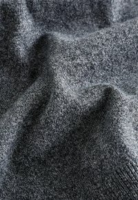 Tela de punto gris con una textura suave, que muestra un sutil patrón variado. El material parece ligeramente elástico y se drapea de manera fluida.