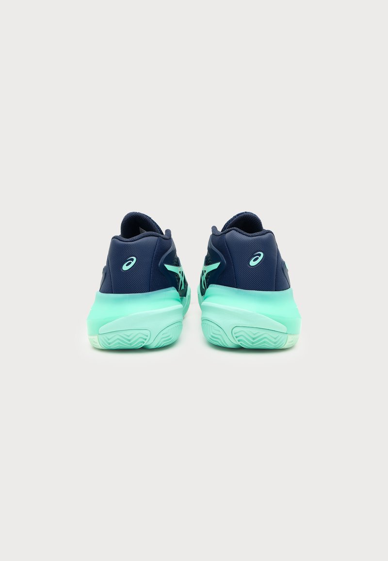 Paire de chaussures de sport bleu marine et vert menthe avec des semelles épaisses, vue de dos sur un fond clair uni.