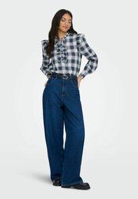 Stribet bluse med flæser ved halsen, parret med højtaljede, vide mørkeblå jeans og sorte platform sko.