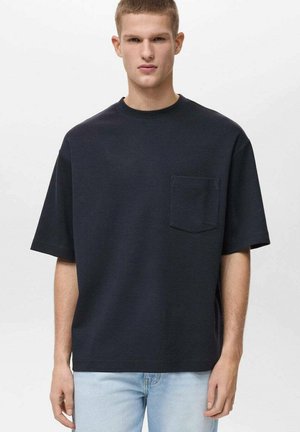 Czarny granatowy t-shirt z bawełny, okrągłym dekoltem, krótkimi rękawami i kieszonką na piersi. Gładka faktura i luźny krój, w połączeniu z jasnymi dżinsami.