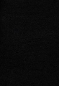 Juodas tekstūruotas audinys su minkštu, pūkuotu paviršiumi ir subtiliu audimo raštu, sukuriantis vienodą tamsų vaizdą.