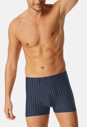 Boxer-briefs rayés bleu marine avec de fines lignes verticales blanches et bleues, ceinture élastique et texture de tissu douce.
