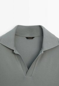 Jasnoszara koszulka polo z teksturowanej tkaniny, z klasycznym kołnierzykiem i dekoltem w kształcie litery V, oznaczona metką "Massimo Dutti".