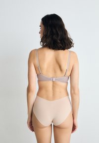 Bra and Panty set in soft, light beige fabric. The bra features adjustable straps and a clasp back. The panty has a smooth, seamless finish.